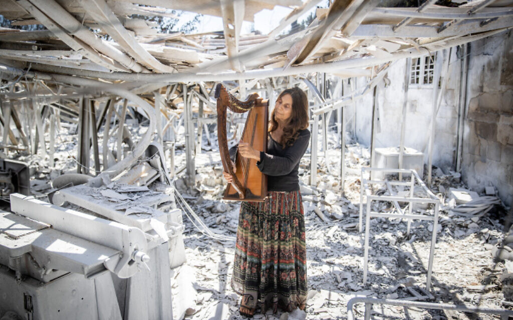 Shoshanna Harari plays a harp in the ruins of her harp-making factory after a forest fire, Moshav Ramat Raziel, near Jerusalem, August 18, 2021. (Yonatan Sindel/Flash90) Shoshanna Harari plays a harp in the ruins of her harp-making factory after a forest fire, Moshav Ramat Raziel, near Jerusalem, August 18, 2021. (Yonatan Sindel/Flash90)