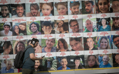 A man walks by posters of people held hostage by Hamas terrorists in Gaza, in Tel Aviv, on January 4, 2024. (Miriam Alster/Flash90)