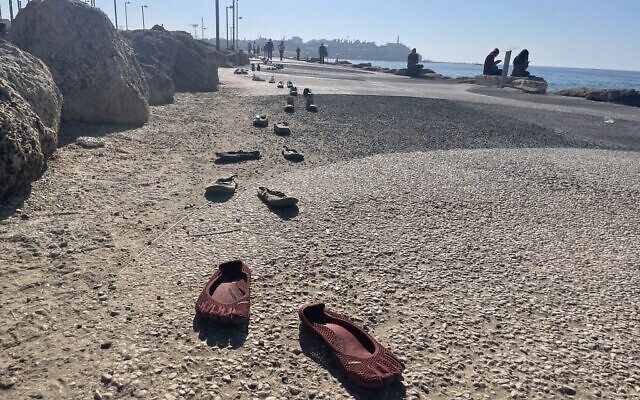 Hundreds of shoes on the Tel Aviv boardwalk to make people think about what it's like to be in the hostages' proverbial shoes, including brothers, Yossi and Eli Sharabi, taken hostage on October 7, 2023 (Jessica Steinberg/Times of Israel)