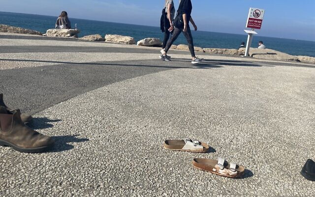 Hundreds of shoes on the Tel Aviv boardwalk to make people think about what it's like to be in the hostages' proverbial shoes, including brothers, Yossi and Eli Sharabi, taken hostage on October 7, 2023 (Jessica Steinberg/Times of Israel)