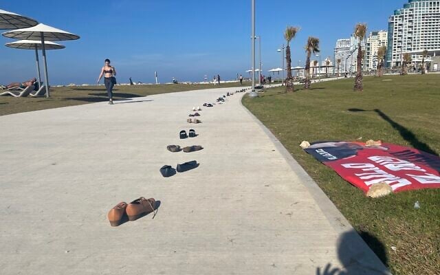 Hundreds of shoes on the Tel Aviv boardwalk to make people think about what it's like to be in the hostages' proverbial shoes, including brothers, Yossi and Eli Sharabi, taken hostage on October 7, 2023 (Jessica Steinberg/Times of Israel)