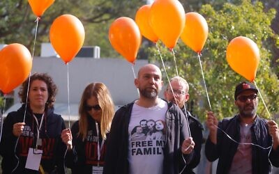 Relatives hold orange balloons at a ceremony in Kibbutz Nir Oz on January 16, 2024 ahead of the first birthday on January 18 of Kfir Bibas, who was taken hostage with his family on October 7 by Hamas terrorists. (Courtesy of the Hostages and Missing Families Forum)