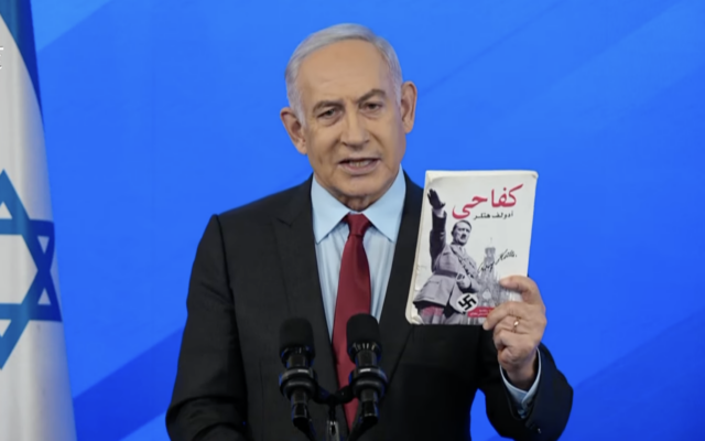Prime Minister Benjamin Netanyahu brandishes a copy of Adolf Hitler's 'Mein Kampf' in Arabic that was recovered from Gaza as he speaks at a press conference about the ongoing war against Hamas, January 27, 2024. (Screenshot) Prime Minister Benjamin Netanyahu brandishes a copy of Adolf Hitler's 'Mein Kampf' in Arabic that was recovered from Gaza as he speaks at a press conference about the ongoing war against Hamas, January 27, 2024. (Screenshot)