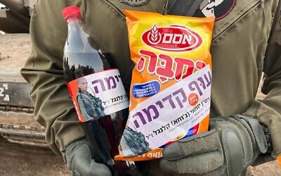 An IDF soldier with Bamba and Coke, part of the 'Operation Juha' civilian charity initiative, in an undated photo. (courtesy)