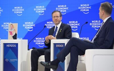 President Isaac Herzog speaks at the World Economic Forum in Davos, Switzerland, Jan. 18, 2024, alongside a photo of Hamas-held Israeli hostage Kfir Bibas. (Amos Ben Gershom/GPO)