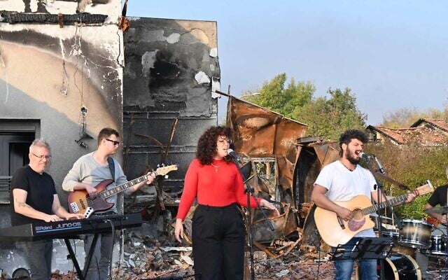 Daniel Weiss, right, performs with a band on the charred remains of his parents' home in Be'eri on January 1, 2024. (Canaan Lidor/Times of Israel) Daniel Weiss, right, performs with a band on the charred remains of his parents' home in Be'eri on January 1, 2024. (Canaan Lidor/Times of Israel)