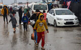 Displaced Palestinians walk in a puddle in rainy weather to get food rations at a makeshift tent camp in Rafah in the southern Gaza Strip on February 2, 2024, amid ongoing battles between Israel and Hamas. (Mohammed ABED / AFP)