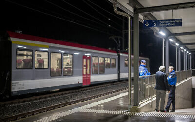 Swiss police officers stand next to a train, where passengers traveling from Yverdon to Sainte-Croix were earlier held hostage, in Essert-Sous-Champvent, western Switzerland on February 8, 2024. (Fabrice Coffrini / AFP)