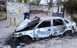 A Palestinian man inspects a car damaged during an alleged attack by Israeli settlers in the village of Asira al-Qibliyah, south of Nablus, in the West Bank on February 13, 2024. (Photo by Jaafar ASHTIYEH / AFP)
