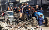People ride in a cart pulled by a tractor past the rubble of a destroyed building and a mosque minaret in Rafah in the southern Gaza Strip on February 14, 2024 (MOHAMMED ABED / AFP)