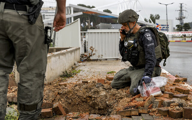 An Israeli policeman inspects the impact crater left by a rocket fired from southern Lebanon where it landed in Safed on February 14, 2024. (Jalaa MAREY / AFP) An Israeli policeman inspects the impact crater left by a rocket fired from southern Lebanon where it landed in Safed on February 14, 2024. (Jalaa MAREY / AFP)