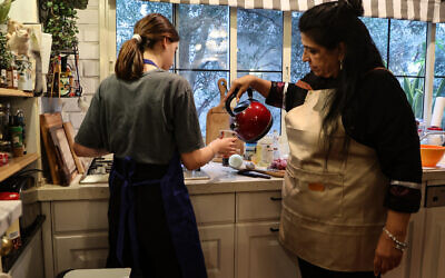 Sigal Chayak prepares a meal with her daughter Shani, in a host kitchen in Tel Aviv on February 13, 2024. (GIL COHEN-MAGEN / AFP)