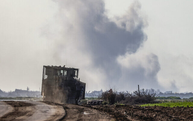 This picture taken from a position in southern Israel near the border with the Gaza Strip shows an Israeli army armored vehicle driving as smoke billows in the background, on February 19, 2024. (Ronaldo Schemidt/AFP) This picture taken from a position in southern Israel near the border with the Gaza Strip shows an Israeli army armored vehicle driving as smoke billows in the background, on February 19, 2024. (Ronaldo Schemidt/AFP)
