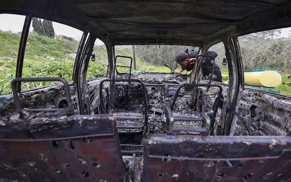 A Palestinian man inspects a car burnt in a reported attack the previous night by Israeli settlers in the village of Burqa, northwest of Nablus in the West Bank, on February 20, 2024. (Zain Jaafar/AFP)