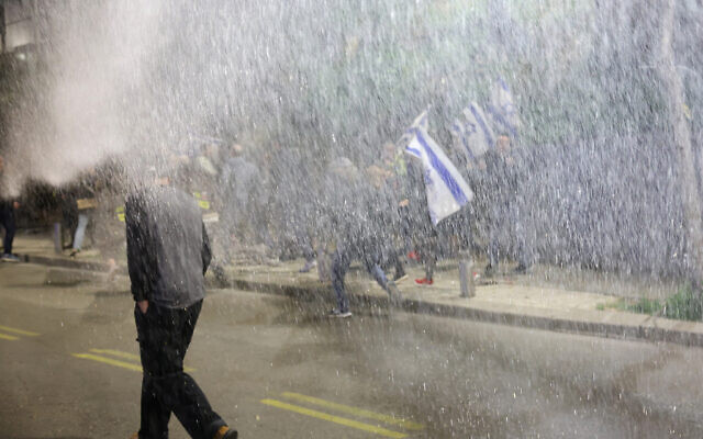 Protesters move away from a water jet used by security forces to disperse them during an anti-government demonstration in Tel Aviv on February 24, 2024 (JACK GUEZ / AFP)