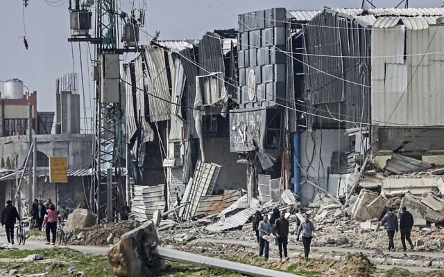 Palestinians walk damaged buildings in the Maghazi camp, which was severely damaged by Israeli strikes on February 27, 2024. (AFP) Palestinians walk damaged buildings in the Maghazi camp, which was severely damaged by Israeli strikes on February 27, 2024. (AFP)