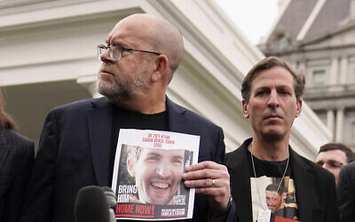 Jonathan Dekel-Chen, left, holds a picture of his son Sagui Dekel-Chen, as he stands next to Ruby Chen, father of Itay Chen, following a White House meeting of families of hostages held in Gaza on December 13, 2023, in Washington, DC. (AP/Evan Vucci)