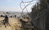 Illustrative: Palestinians displaced by the Israeli offensive in the Gaza Strip sit next to the border fence with Egypt in Rafah, Wednesday, January 24, 2024. (AP Photo/Hatem Ali)