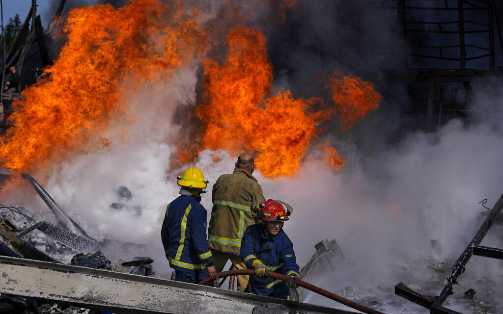 Firefighters working to extinguish a fire at a destroyed warehouse that Israel says is a Hezbollah arms depot, still burning after it was hit a day earlier in Israeli airstrikes, at an industrial district in the southern coastal town of Ghazieh, Lebanon, Feb. 20, 2024 (AP Photo/Bilal Hussein)