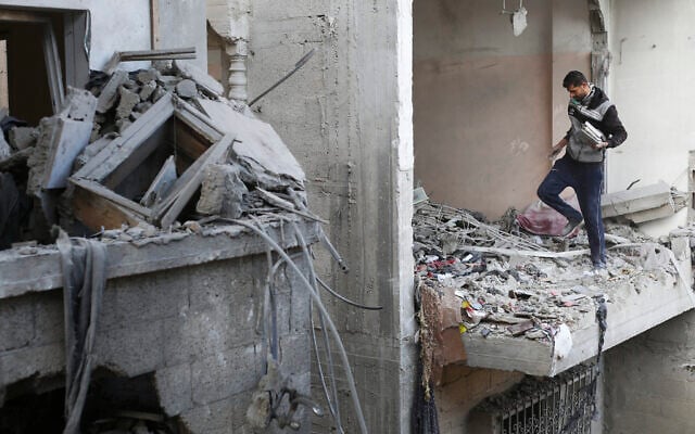 A Palestinian man collects books after an alleged Israeli strike on a residential building in Rafah, Gaza Strip, February 21, 2024. (AP Photo/Hatem Ali)