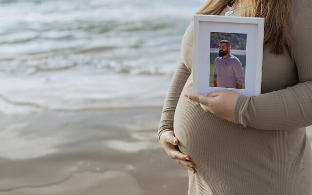 A pregnant Shahar Naim holds a picture of her husband Amir Naim, who was killed by Hamas terrorists while defending Kibbutz Erez on October 7, 2023. (Courtesy)