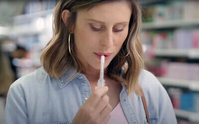 A woman (played by actor and influencer Alina Levy) uses Salistick saliva pregnancy test while shopping at a drugstore in Israel in YouTube ad for the new product, March 2024. (Screenshot/YouTube)