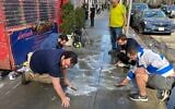 On their hands and knees, a group of Jewish volunteers scrub pro-Palestinian graffiti from the sidewalk outside of Effy's Café, a kosher restaurant on the Upper West Side, March 17, 2024. (Jackie Hajdenberg/JTA)