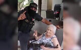 Esther Cunio is forced to pose for a photo with a Hamas terrorist who invaded her home at Kibbutz Nir Oz during the terror group's onslaught in southern Israel, October 7, 2023. (Courtesy)
