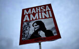 FILE - A woman holds a placard with a picture of Iranian woman Mahsa Amini during a protest against her death, in Berlin, Germany, on September 28, 2022. (AP Photo/Markus Schreiber)