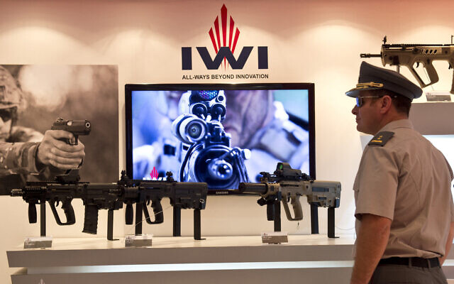 Illustrative: A visitor looks at Israeli IWI weapons on display at the XVIII Air and Space Fair (FIDAE) in Santiago on March 28, 2014. (AFP Photo/Martin Bernetti)