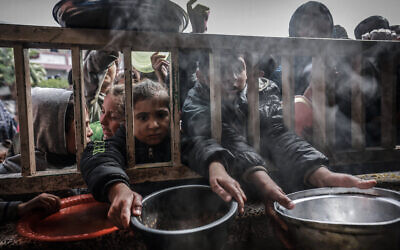 Displaced Palestinian children gather to receive food at a government school in Rafah in the southern Gaza Strip on February 19, 2024. (Mohammed Abed/AFP)