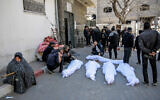 People mourn at Al-Shifa Hospital in Gaza City over the bodies of Palestinians killed in an early morning incident when residents rushed toward aid trucks in Gaza City on February 29, 2024 (AFP)