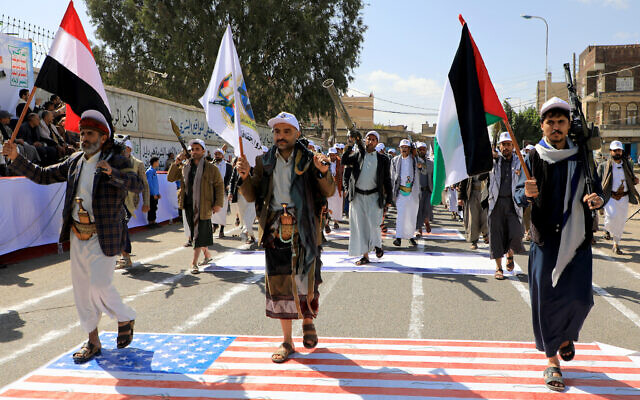 Armed Yemeni men step on a US flag painted on the asphalt in the Houthi-run capital Sanaa on February 29, 2024. (MOHAMMED HUWAIS / AFP) Armed Yemeni men step on a US flag painted on the asphalt in the Houthi-run capital Sanaa on February 29, 2024. (MOHAMMED HUWAIS / AFP)