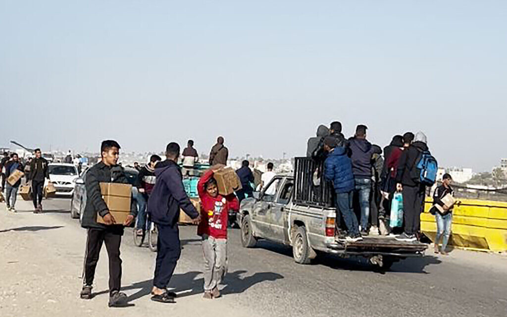 People carry food parcels that were air-dropped from US aircraft above a beach in the Gaza Strip, on March 2, 2024.(AFP photo)