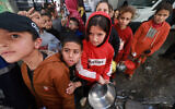 Illustrative. Palestinian children receive cooked food rations as part of a volunteer youth initiative in Rafah in the southern Gaza Strip, on March 5, 2024. (MOHAMMED ABED / AFP)