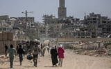 Displaced Palestinians carry their belongings through a street in Khan Younis in the southern Gaza Strip on March 6, 2024. (AFP)