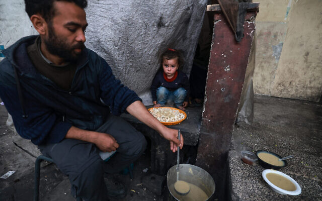 A Palestinian man prepares plates of food before an iftar meal, breaking of fast, on the second day of the Muslim holy fasting month of Ramadan, at a camp for displaced people in Rafah in the southern Gaza Strip on March 12, 2024. (Mohammed Abed/AFP)