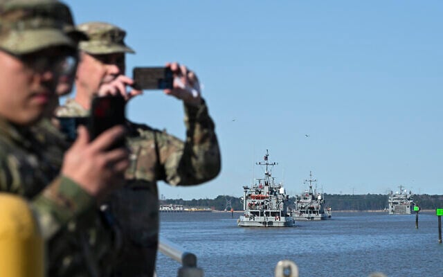 US Army soldiers take photographs of the USAV Monterrey (not pictured) as it pulls away from the pier at the Joint Base Langley-Eustis during a media preview of the 7th Transportation Brigade deployment in Hampton, Virginia, on March 12, 2024.(Roberto Schmidt/AFP)