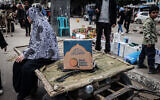 A Palestinian woman sits on a cart next to a box of food rations provided by charity World Central Kitchen at a makeshift street market in Rafah in the southern Gaza Strip on March 14, 2024. (Mohammed Abed/ AFP)