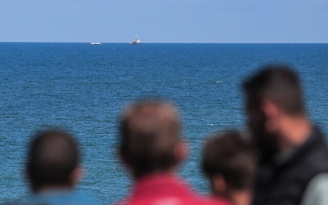 Palestinian men watch as the Open Arms maritime vessel that set sail from Larnaca in Cyprus carrying humanitarian aid, approaches the coast of Gaza City on March 15, 2024. (AFP)