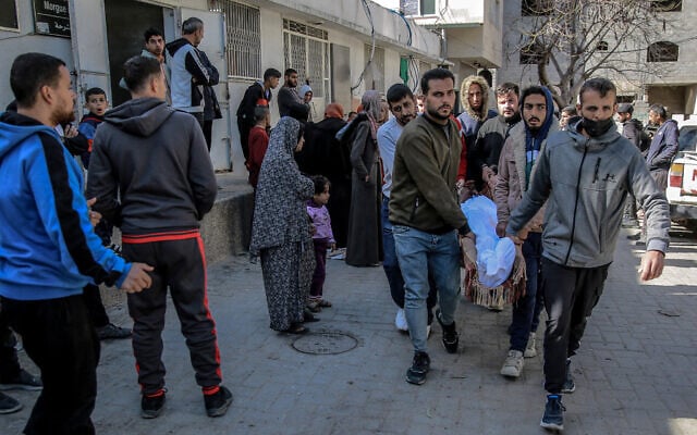 Palestinians carry away the body of a man from the morgue of the Al-Shifa hospital in Gaza City, March 15, 2024. (AFP) Palestinians carry away the body of a man from the morgue of the Al-Shifa hospital in Gaza City, March 15, 2024. (AFP)
