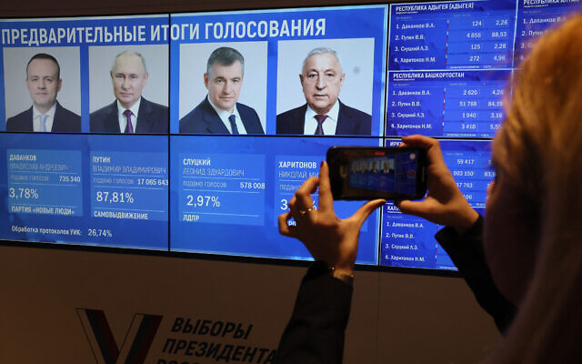 A woman takes a photograph with her mobile telephone of a screen with preliminary voting results in the Russian presidential election at the Central Election Commission in Moscow on March 17, 2024. (STRINGER / AFP) A woman takes a photograph with her mobile telephone of a screen with preliminary voting results in the Russian presidential election at the Central Election Commission in Moscow on March 17, 2024. (STRINGER / AFP)