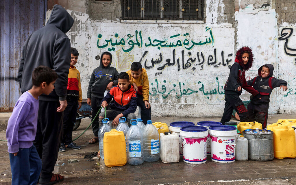 A boy fills water containers from a hose in Rafah in the southern Gaza Strip on March 19, 2024 (MOHAMMED ABED / AFP)