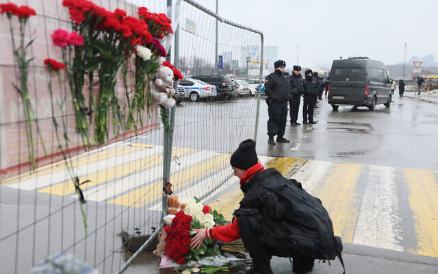 Russian law enforcement officers stand guard as a woman lays flowers at a makeshift memorial in front of the Crocus City Hall, a day after a terror shooting attack in Krasnogorsk, outside Moscow, left at least 93 people dead on March 23, 2024. (Photo by STRINGER / AFP) Russian law enforcement officers stand guard as a woman lays flowers at a makeshift memorial in front of the Crocus City Hall, a day after a terror shooting attack in Krasnogorsk, outside Moscow, left at least 93 people dead on March 23, 2024. (Photo by STRINGER / AFP)