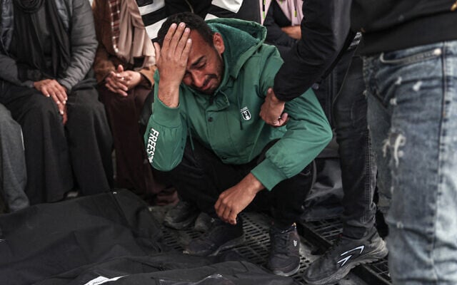 Palestinians mourn over the covered bodies of relatives, killed in an overnight Israeli strike, at the al-Najjar hospital in Rafah in the southern Gaza Strip on March 25, 2024. (Said Khatib/AFP)