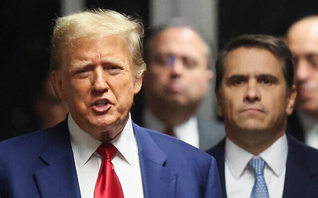 Former US president Donald Trump speaks to the press in a hallway outside the courtroom during a recess in a hearing to determine the date of his trial for allegedly covering up hush money payments linked to extramarital affairs, at Manhattan Criminal Court in New York City on March 25, 2024. (Brendan McDermid/Pool/AFP)