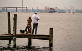 People look out toward the Francis Scott Key Bridge following its collapse after the Singapore-flagged Dali container ship collided with it along the Patapsco River on March 26, 2024 in Baltimore, Maryland. (Kent Nishimura/AFP)