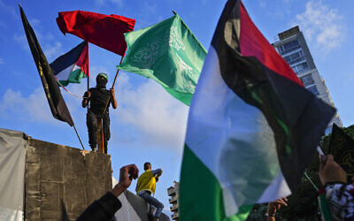 A man holds Palestinian and Hamas flags at a protest near the British embassy in Beirut, Nov. 14, 2023. (AP Photo/Hassan Ammar)