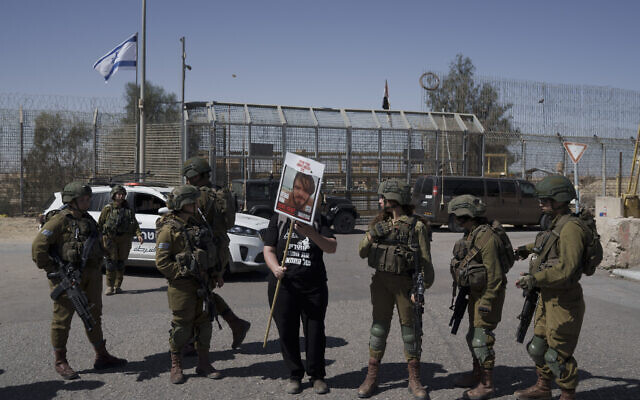 A woman holds up a picture of a hostage held captive by Hamas in the Gaza Strip as she stands next to Israeli soldiers at Israel's Nitzana border crossing with Egypt in southern Israel, March 5, 2024, protesting against the delivery of humanitarian aid to the Gaza Strip until all hostages are released. (AP/Leo Correa) A woman holds up a picture of a hostage held captive by Hamas in the Gaza Strip as she stands next to Israeli soldiers at Israel's Nitzana border crossing with Egypt in southern Israel, March 5, 2024, protesting against the delivery of humanitarian aid to the Gaza Strip until all hostages are released. (AP/Leo Correa)
