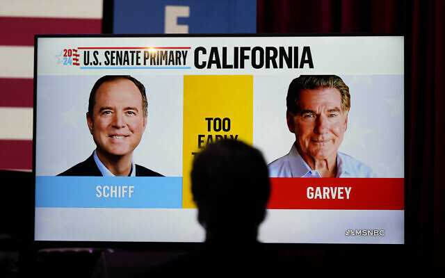 Photos of US Representative Adam Schiff, a Democrat, at left, a USSenate candidate, and his Republican opponent Steve Garvey flash on a television screen during an election night party for Schiff, March 5, 2024, in Los Angeles. (AP Photo/Jae C. Hong)